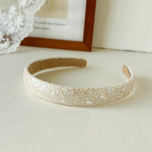 Detail of shimmering champagne sequins on a wide headband with iridescent reflections
