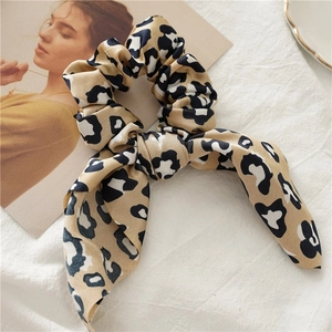 Detail of elegant leopard print satin scrunchie with bow on textured fabric background