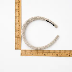 Detail of beige knitted headband showing thick yarn texture and handmade label with measurement