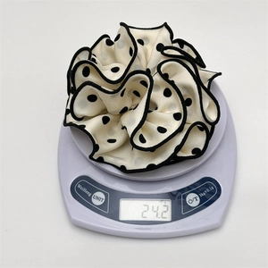 Detailed view of polka dot scrunchie on electronic scale showing 24.2g weight
