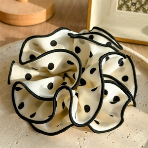 Close-up of a large beige scrunchie with black polka dots on a stone tray
