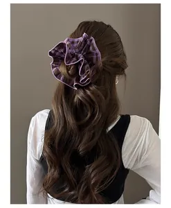 Close-up of a large purple plaid fabric scrunchie worn on long wavy hair in autumn style