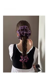 Detailed view of purple plaid fabric scrunchies styled on a long brunette ponytail