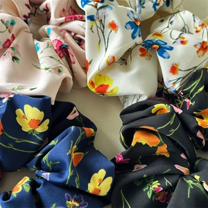 Detailed close-up of floral satin scrunchies in pink, white, navy, and black patterns