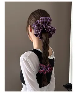 Detailed back view of purple plaid and deep red fabric scrunchies on a ponytail