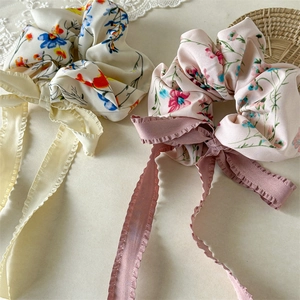 Close-up of floral fabric hair scrunchies with long ribbons on a lace background