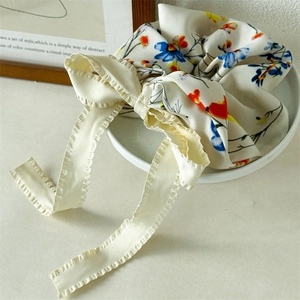Detailed view of floral scrunchie with large cream bow and delicate ruffled edges on porcelain