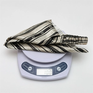 Ethnic style striped headwrap weighting 10g on a scale to show its lightweight feel