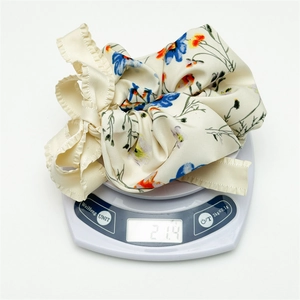 Floral print scrunchie with bow detail weighing 21.4g on a digital scale closeup
