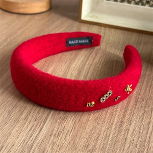 Detailansicht rotes Wollstirnband mit goldenen Glücksbringern und Hand-made-Label