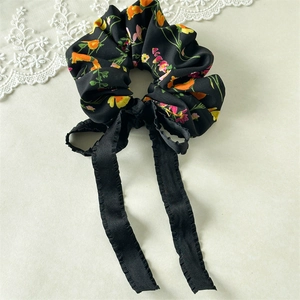 Close-up of black floral scrunchie with long ribbons and vibrant flower prints