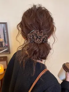 Vue détaillée d'un chouchou léopard en daim avec étiquette faite main sur un chignon