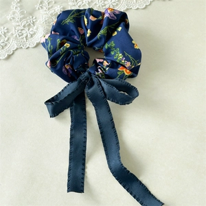 Detail of floral scrunchie with navy blue long ribbon tails on lace background