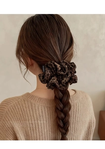 Détail du chouchou en daim léopard avec étiquette faite main sur une coiffure tressée