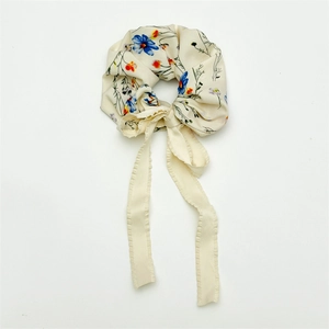 Detail of floral chiffon hair scrunchie with long ribbon bow in cream color