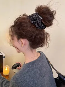 Détail d'un chouchou en daim à imprimé léopard gris porté sur un chignon élégant