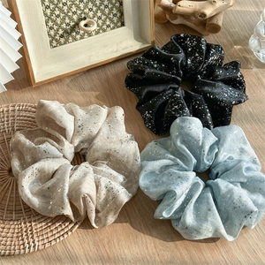 Flat lay of three large organza scrunchies in beige black and blue with silver glitter
