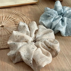 Detail of champagne and blue fabric scrunchies with silver foil print on wooden table