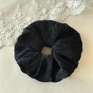Détail d'un chouchou noir avec texture plissée élégante sur fond de dentelle blanche