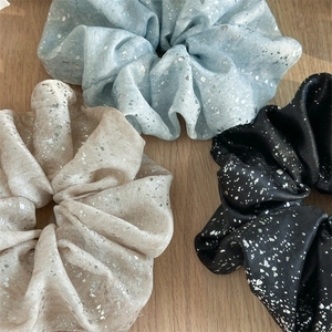 Three oversized hair scrunchies with silver splatter pattern on wood surface
