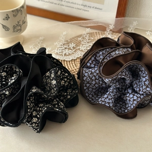Detail of floral oversized scrunchies in black and brown satin fabric on a vintage desk