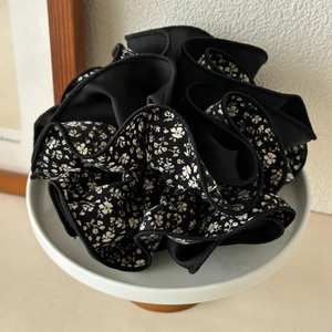 Detail of a large layered floral scrunchie with black satin and cream flower patterns