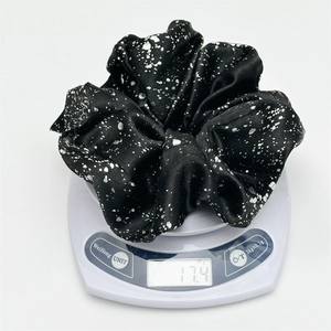 Detail showing the lightweight 17.4g silver-foiled fabric scrunchie on a digital scale