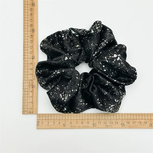 Detail view of a 15cm oversized black satin scrunchie with silver foil dot pattern