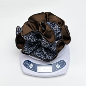 Macro view of floral hair scrunchie on scale weighing 43.9g for product weight verification