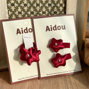 Detail of red fabric star hair accessories with pearl accents on a display card