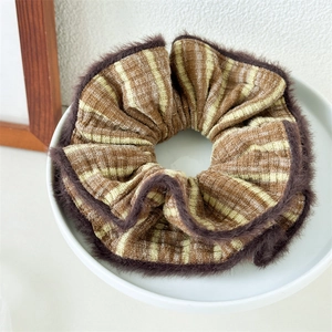 Detailed view of winter brown striped scrunchie with soft faux fur trim on white plate