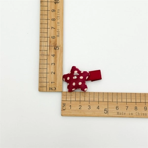 Detail showing red star hair clip with white dots and pearl bead measured by wooden rulers
