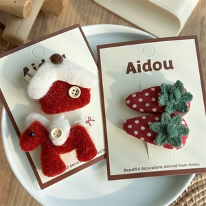 Détails de barrettes à cheveux en feutre rouge et fraise sur cartes dans une assiette blanche