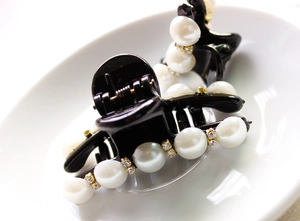Detailed view of black hair claw clip featuring rows of faux pearls and sparkling rhinestones