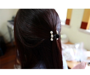 Detail of small black resin hair claw clip with pearls and rhinestones on dark hair