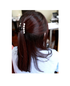 Macro detail of small black hair claw clip with white pearls on dark auburn hair