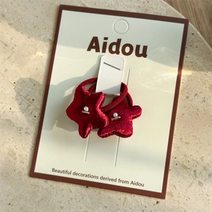 Detail of red velvet star hair ties with white pearls and silver beads on a display card