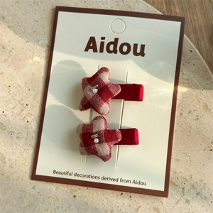 Detail of red and beige checkered star hair clips with white pearls on a gift card