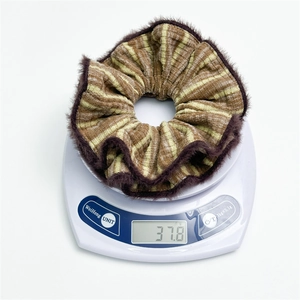 Close-up of striped scrunchie with faux fur trim weighing 37.8g on white digital scale