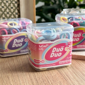 Close-up of macaron colored high-stretch hair ties in a clear storage box on a wood table