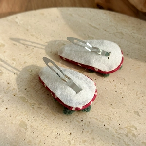 Détail de barrettes fraises rouges avec clips métalliques et doublure en feutrine
