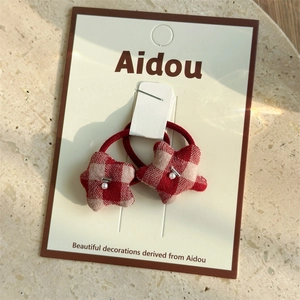 Close-up of red plaid star hair ties with pearl accents on a display card