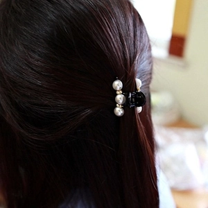 Elegant black hair claw clip with white pearls and gold accents on brunette hair
