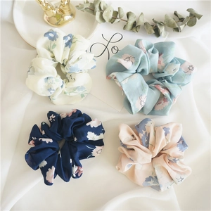 Close-up of four floral chiffon hair scrunchies in pastel colors with elegant patterns