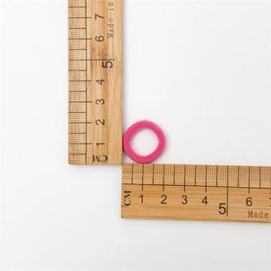 Detailed view of pink elastic hair tie with 2cm diameter measurement on scale