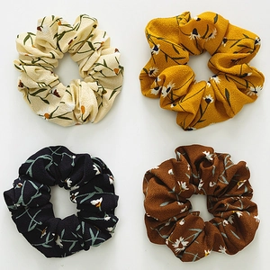 Detail view of four floral chiffon hair scrunchies in cream yellow navy and brown