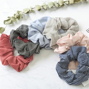 Detail showing striped fabric scrunchies in six colors on white marble background