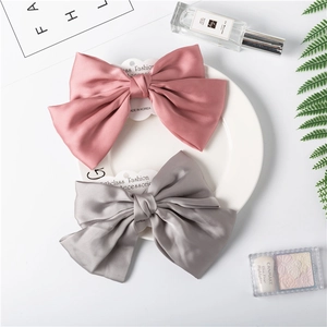 Detail of pink and grey satin chiffon bow hair clips on a white ceramic plate