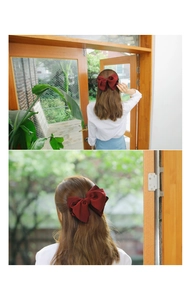 Close-up of a large three-layer burgundy chiffon bow hair clip worn on long wavy hair