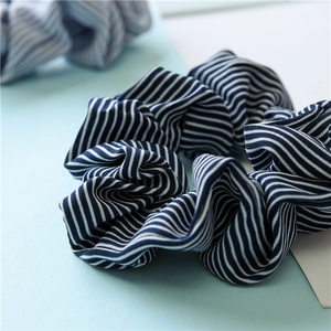 Detailed close-up showing fabric texture of striped elastic scrunchies on blue background